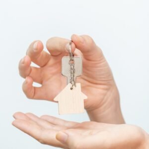 Hands holding house key on white background closeup - real state moving relocation concept