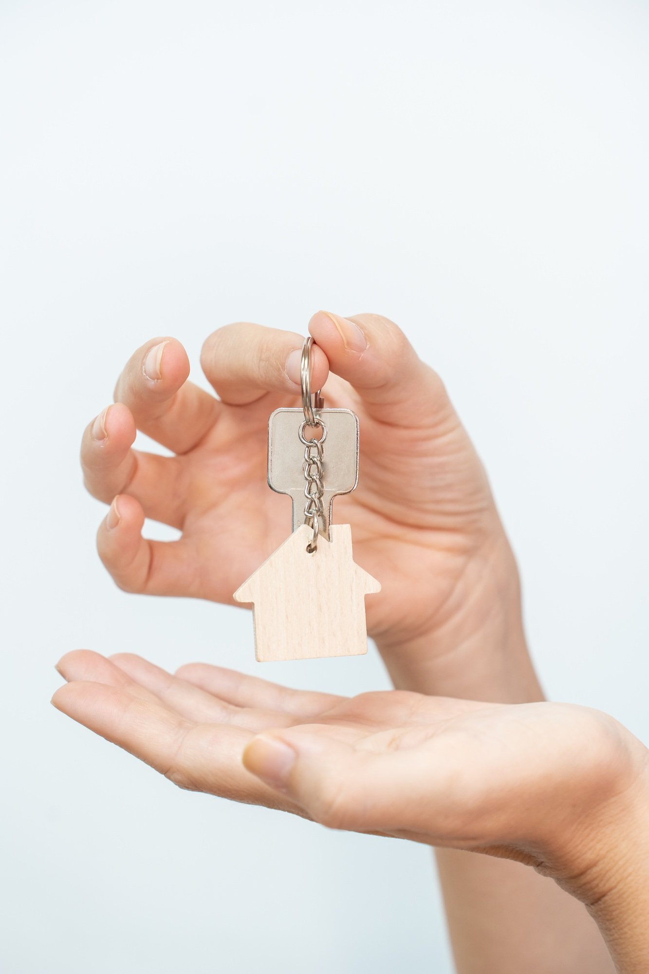 Hands holding house key on white background closeup - real state moving relocation concept